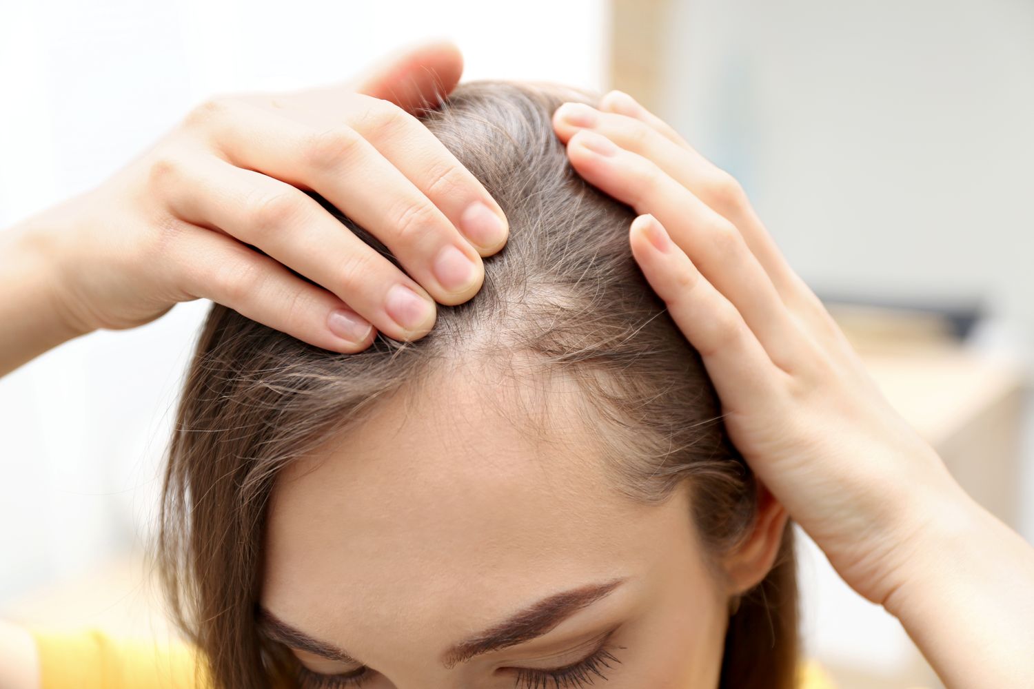 A woman checking regrowth along her parting
