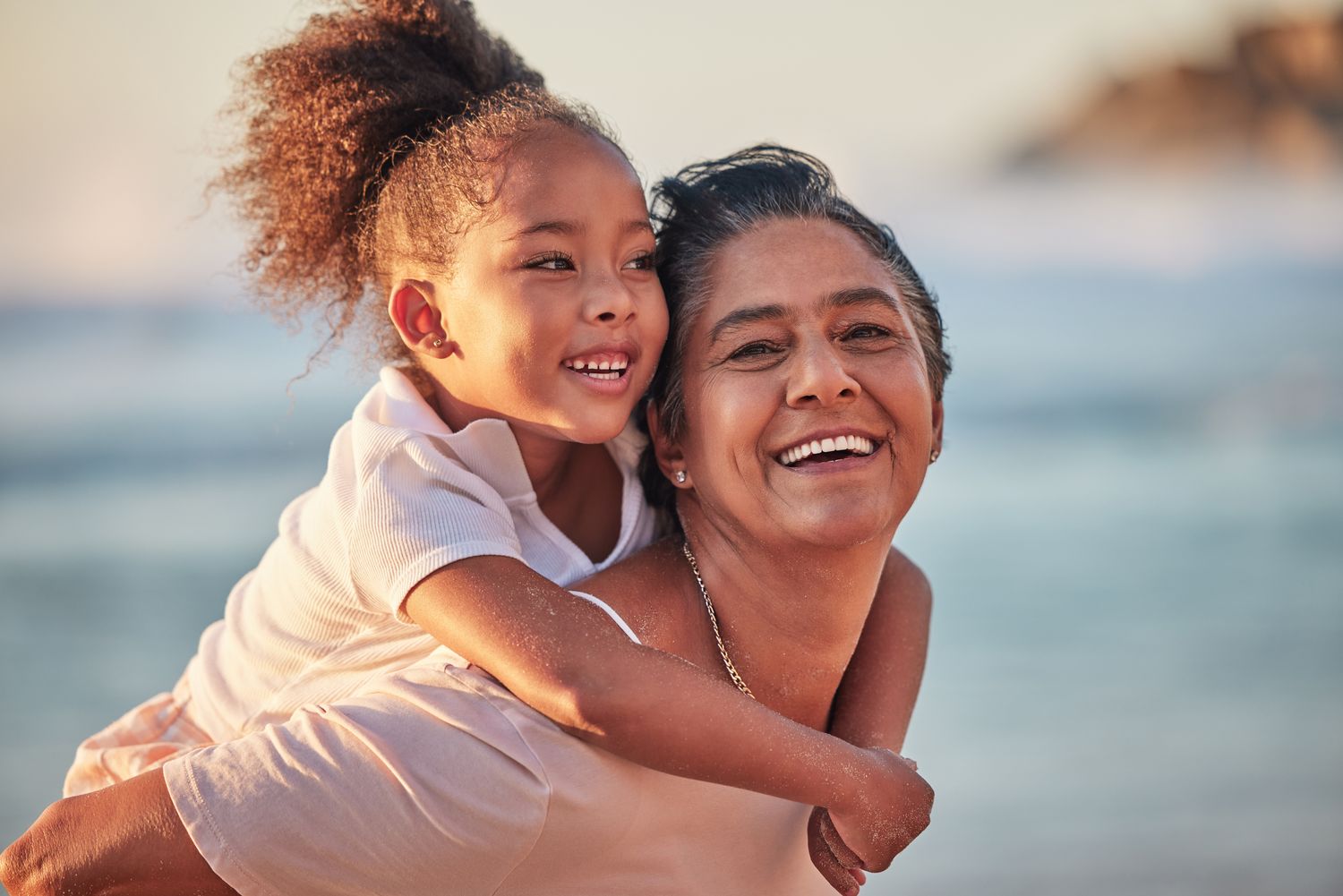 A grandmother and girl laughing together at the beach