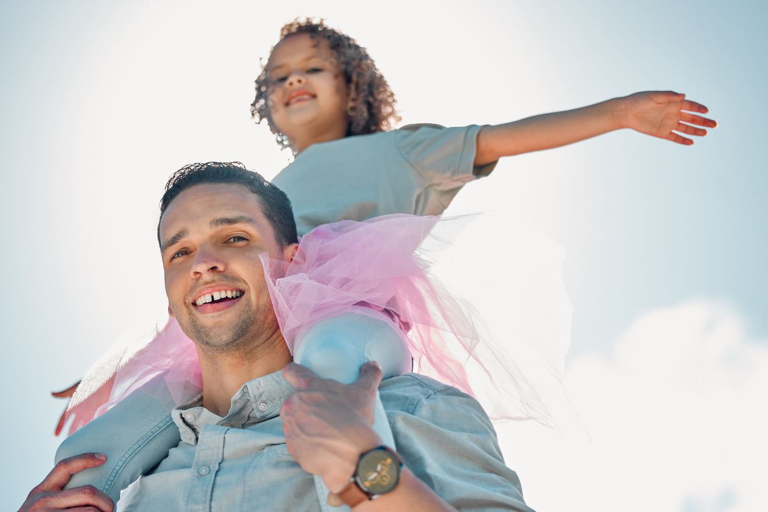 A father carrying his smiling daughter on his shoulders
