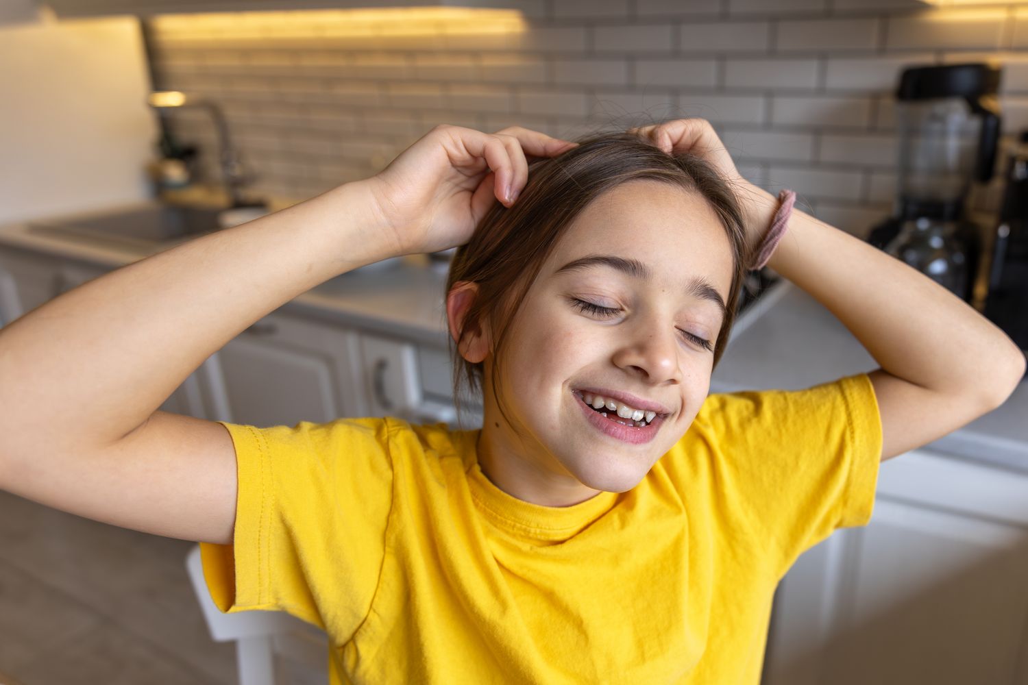 A young girl smiling with her hands in her hair