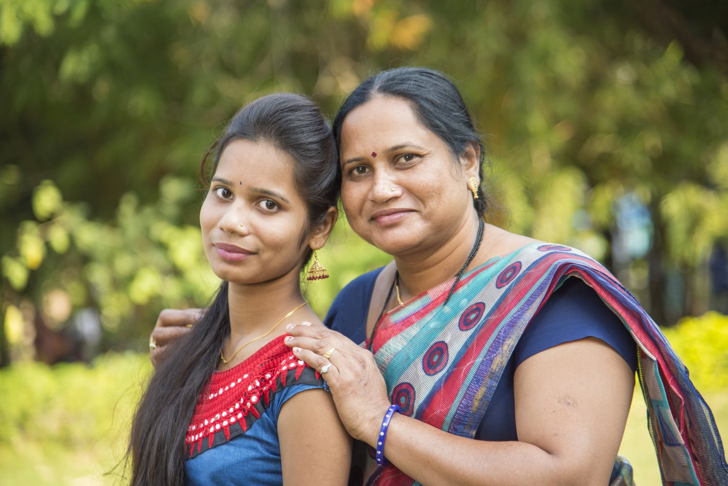 Two women smiling together outdoors in a park